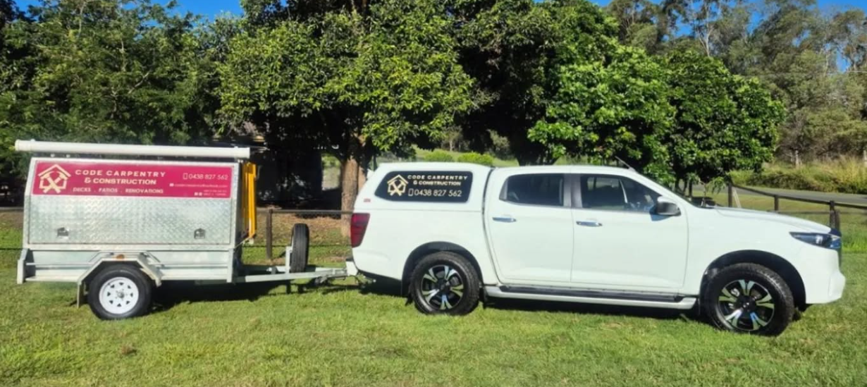 Code Carpentry & Construction work ute and signage trailer in a local park setting